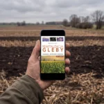 Rolnik trzyma telefon z e-bookiem „Rewitalizacja gleby” na polu